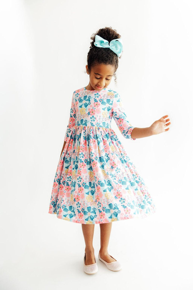 Girl in Floral Garden 3/4 sleeve twirl dress with pastel florals and teal bow.