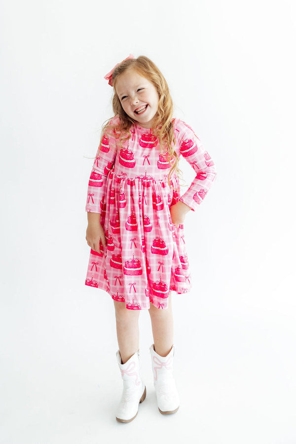 Make a Wish L/S Pocket Twirl Dress in pink cake-print fabric with long sleeves, scoop-back neckline, and pockets.