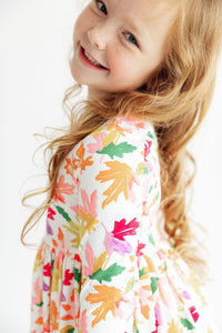 Child wearing Falling Leaves 3/4 Sleeve Pocket Twirl Dress with a colorful leaf print.