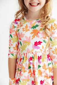 Girl wearing Falling Leaves 3/4 Sleeve Pocket Twirl Dress with colorful leaf print and a twirly full skirt.