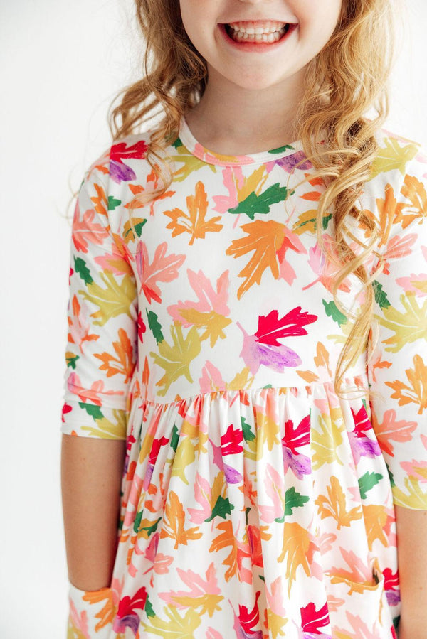 Girl wearing Falling Leaves 3/4 Sleeve Pocket Twirl Dress with colorful leaf print and a twirly full skirt.