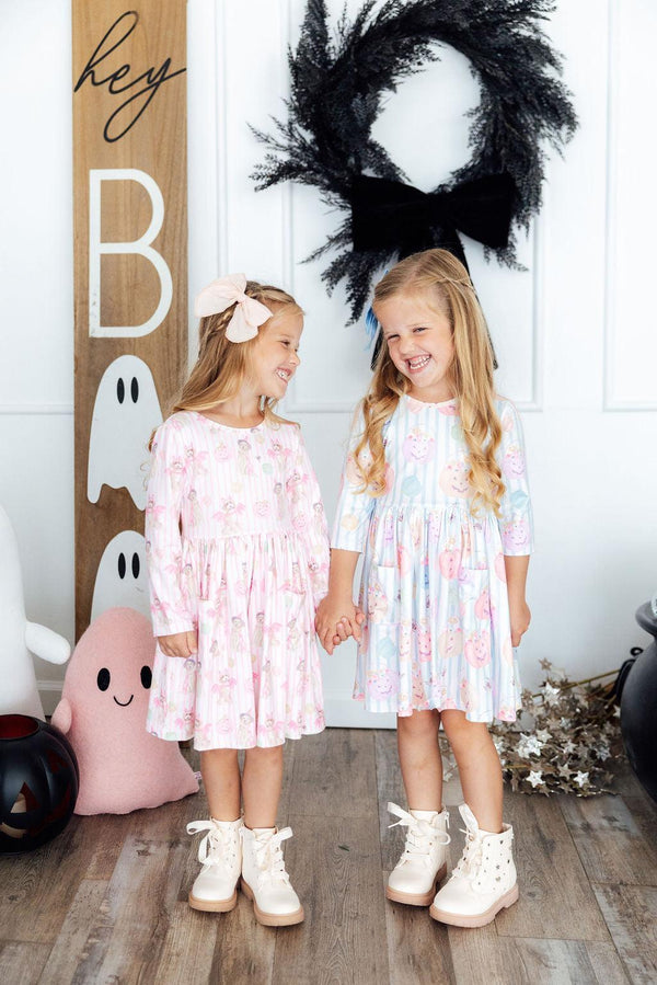 Two girls wear Here for the Candy 3/4 Sleeve Pocket Twirl Dress for Girls in pastel candy-print patterns.