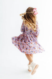 Toddler girl twirling in a Halloween print 3/4 sleeve dress with pockets. Features a scoop back for easy wear and a fun, flowy fit for play.