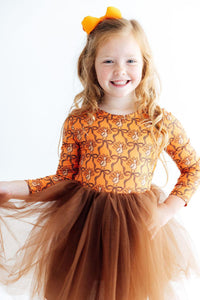 Girl in turkey print long sleeve dress with brown tutu skirt and orange bow. Perfect festive outfit for special occasions or everyday play.