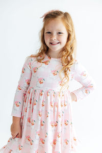 Girl wearing pink gingham Storybook Santa long sleeve dress with ruffle hem and full skirt for twirling.