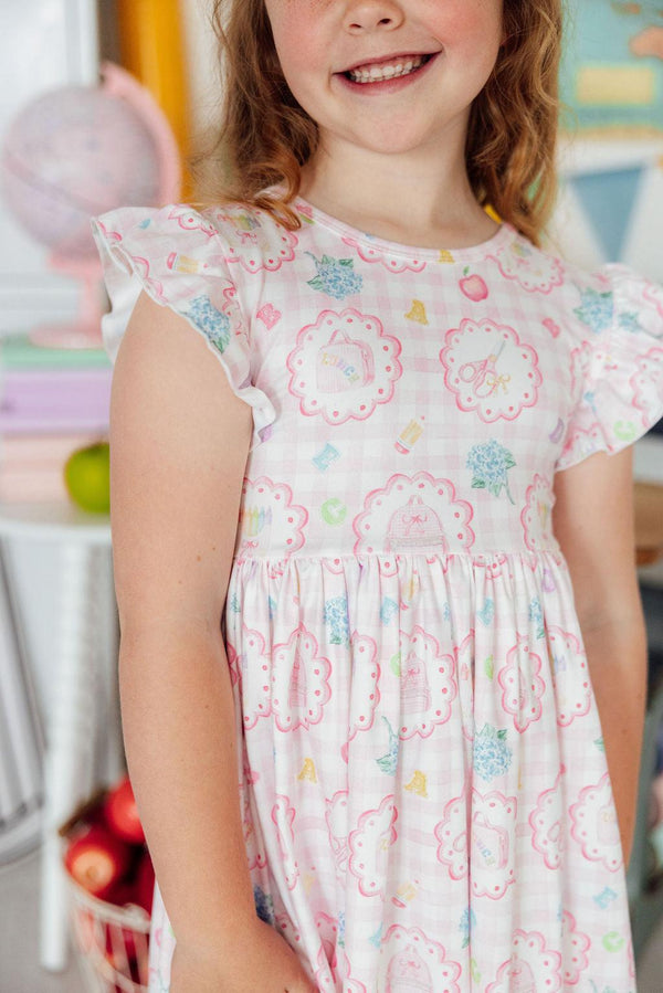 Smiling toddler girl wearing Apple of My Eye Flutter Sleeve Twirl Dress in pink pattern.