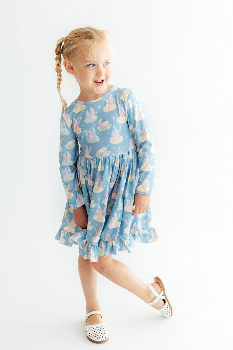 Girl wearing blue long sleeve ruffle hem twirl dress with castle print, perfect for school or play.