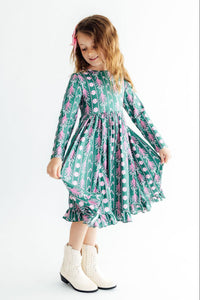 Girl wearing Christmas Treats Long Sleeve Ruffle Hem Twirl Dress in green with pink pattern, twirling.