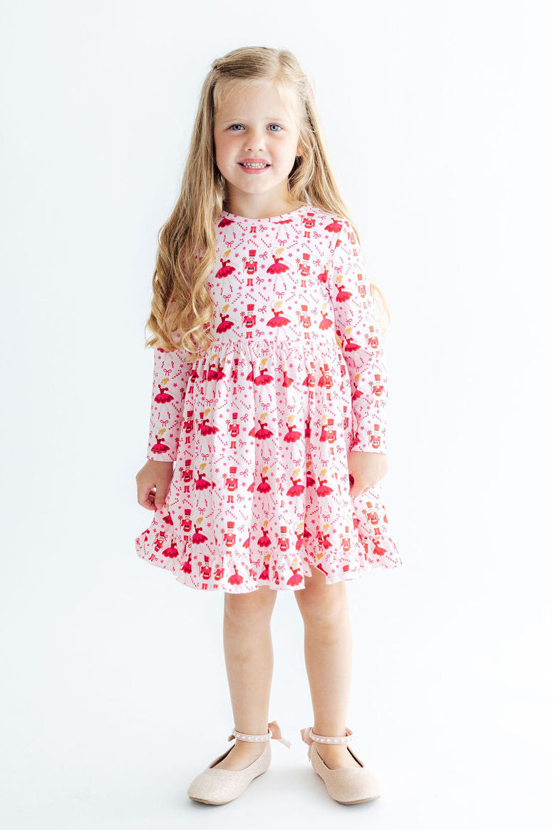 Girl wearing Candy Cane Ballet Long Sleeve Ruffle Hem Twirl Dress in pink with red ballet prints, full twirl skirt.