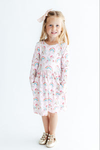 Girl in pink unicorn print long sleeve dress with side pockets and gold bow shoes for festive play.