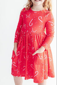 Red long sleeve pocket dress with candy cane and bow print. Soft full twirl skirt perfect for holidays and everyday play.