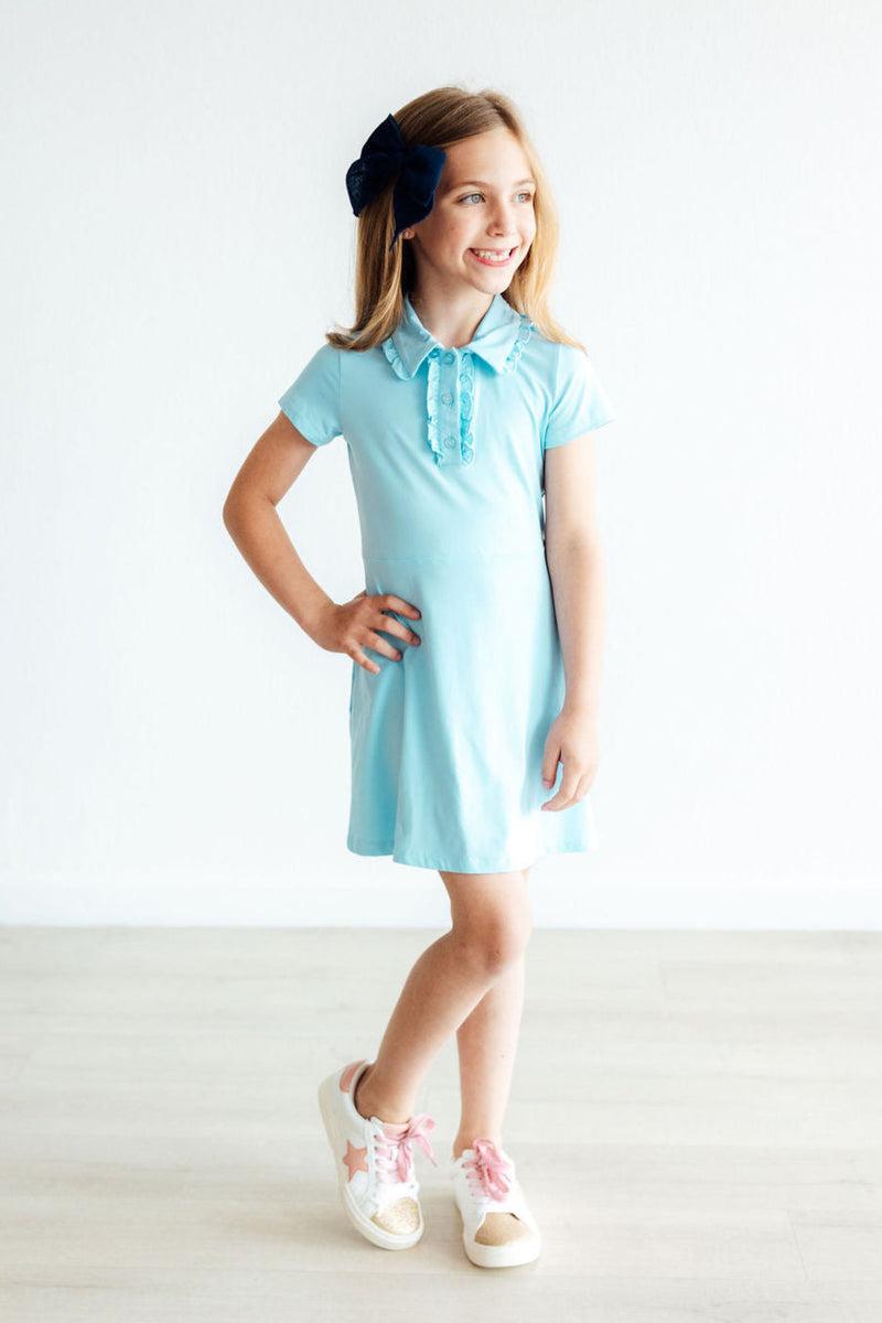 Child learning to dress independently in the Bluebird S/S Polo Dress, showcasing the easy pull-on style for little ones.