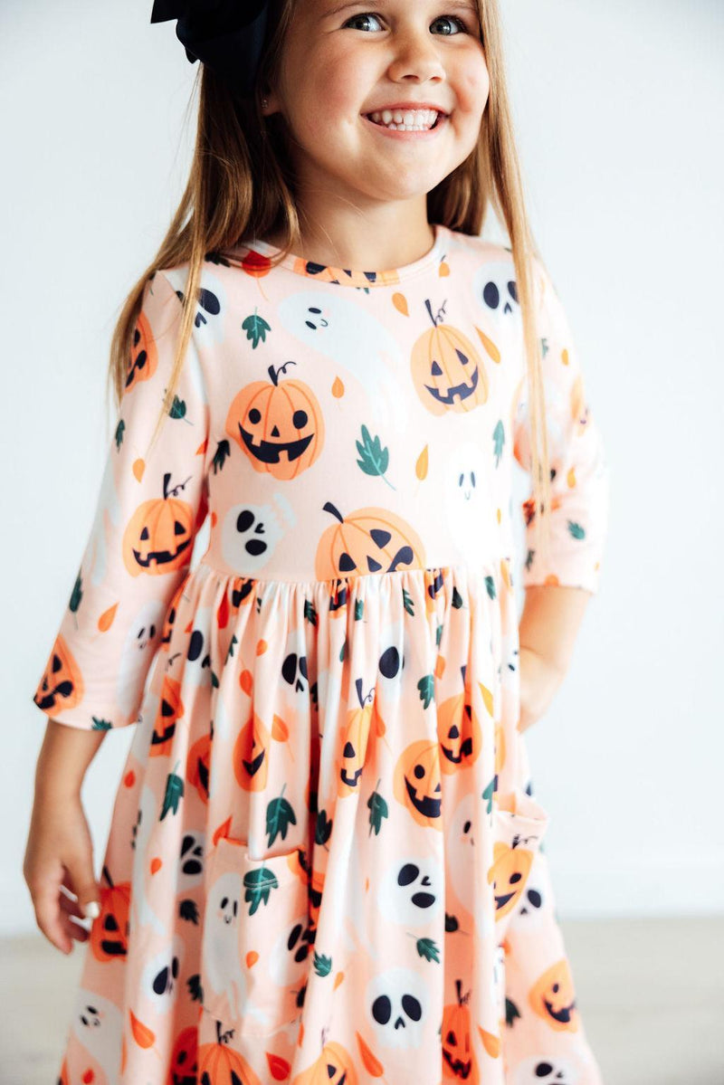 Bright and festive Pumpkin Peekaboo 3/4 Sleeve Pocket Twirl Dress showcased on a hanger, ideal for stylish little explorers.