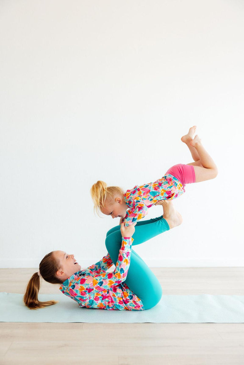 Happy girl enjoying yoga with her mother, both in colorful outfits including Turbo Teal Active Leggings for Girls, showing versatility for active moments.