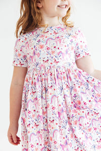 Young girl wearing Whimsical Woods Short Sleeve Pocket Twirl Dress with a unicorn and floral print.