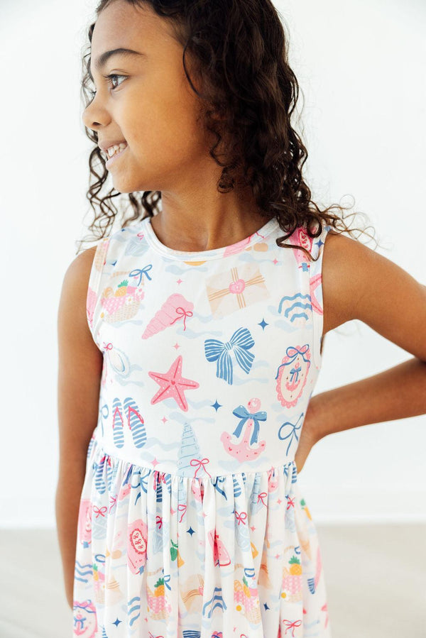 Girl in Seaside Sweetheart Tank Twirl Dress with seashell and starfish print, smiling in a side profile.