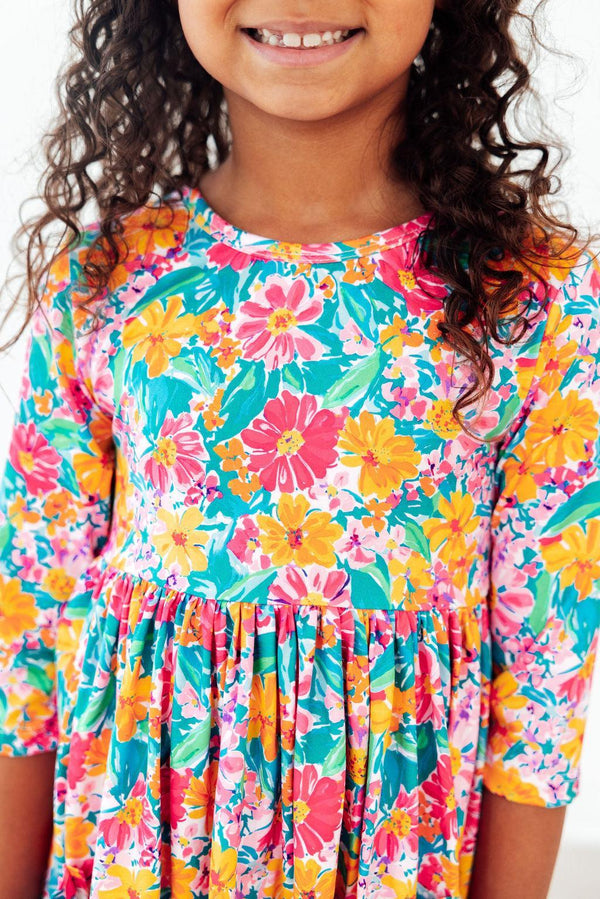 Girl wearing Floral Fiesta 3/4 Sleeve Twirl Dress in bright floral print.