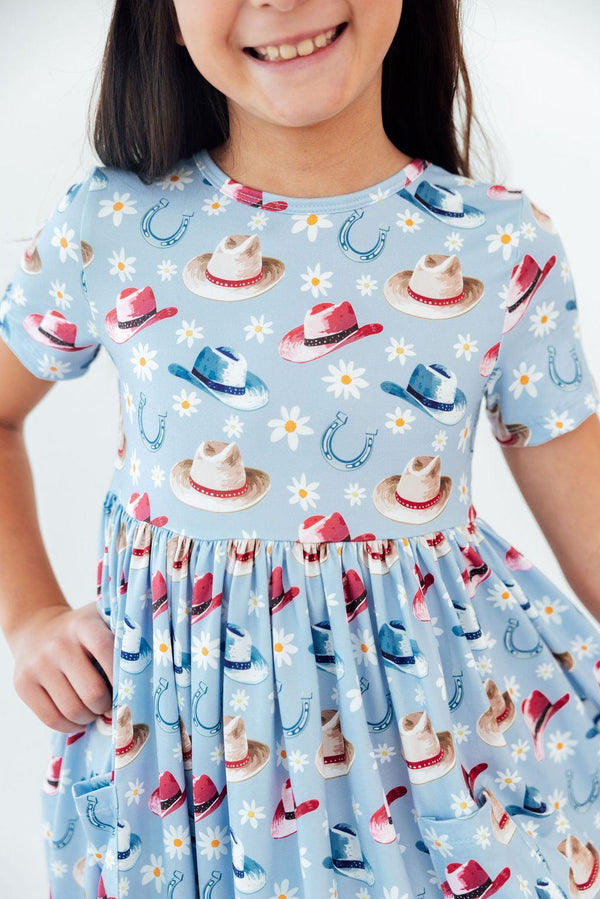Detail shot of the Tip Your Hat Short Sleeve Pocket Twirl Dress For Girls showcasing its soft stretch fabric and playful twirl-ready design.