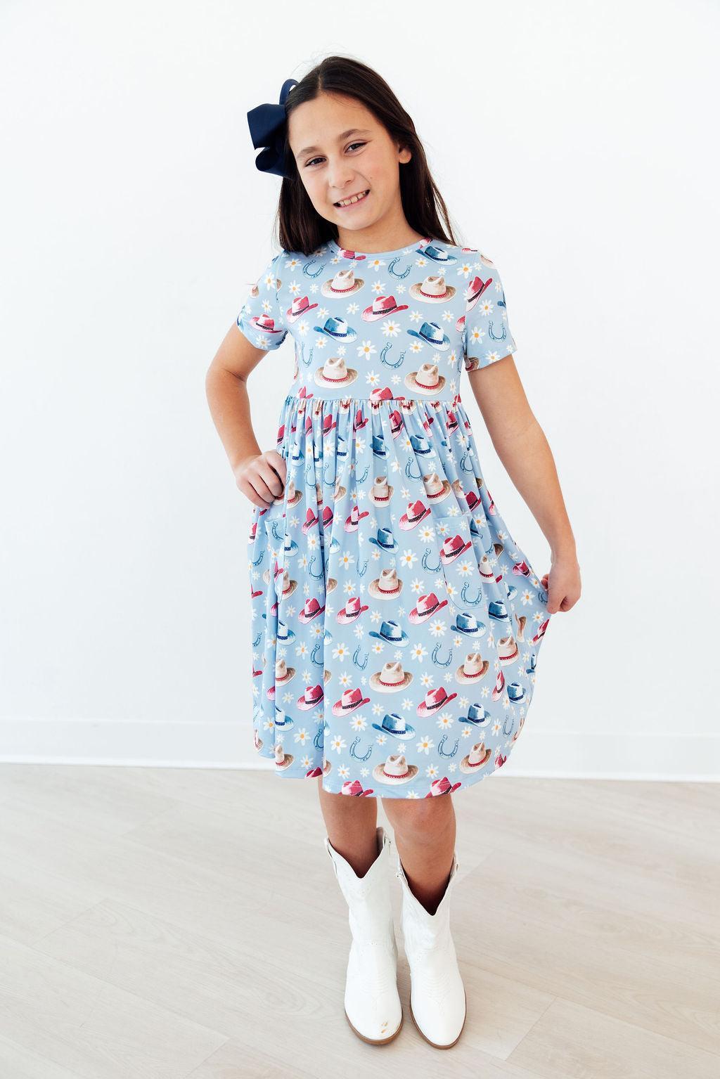 Close-up view of the Tip Your Hat Short Sleeve Pocket Twirl Dress For Girls, emphasizing the stylish higher neckline and fun pocket details.