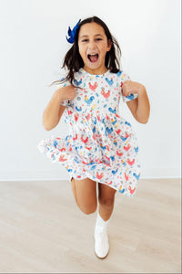 Full view of a child wearing the Rainbow Roosters Short Sleeve Pocket Twirl Dress For Girls, demonstrating its twirl silhouette and versatility as a pocket dress for girls.