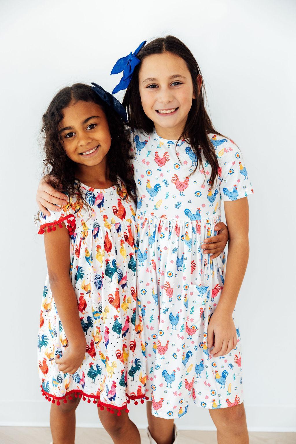 Side view of the Rainbow Roosters Short Sleeve Pocket Twirl Dress For Girls, highlighting the modest neckline and scoop back, embodying a charming pocket dress for girls.