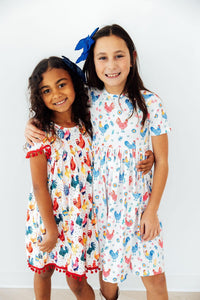 Side view of the Rainbow Roosters Short Sleeve Pocket Twirl Dress For Girls, highlighting the modest neckline and scoop back, embodying a charming pocket dress for girls.