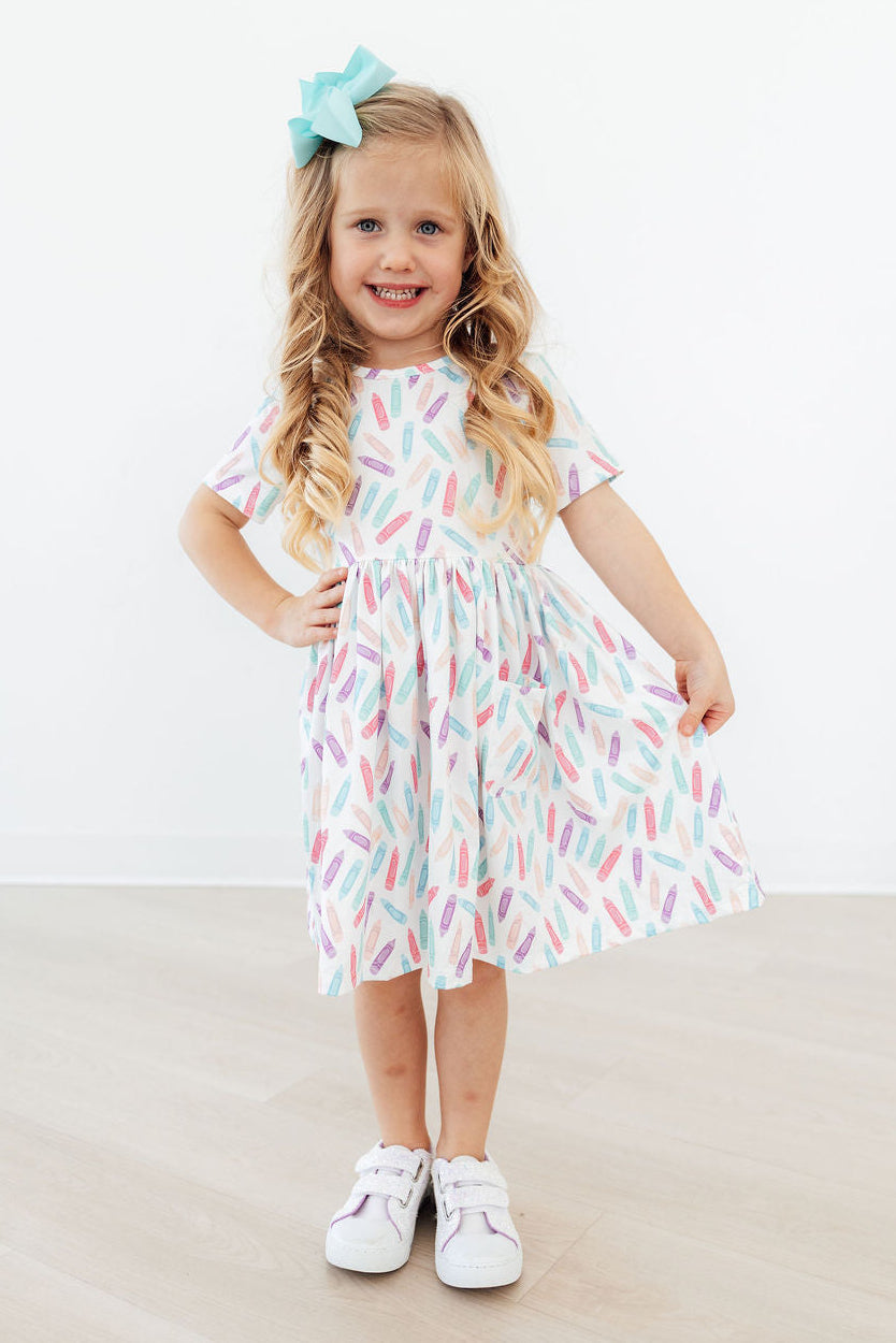 Close-up of the Color Crayons Short Sleeve Pocket Twirl Dress for Girls showing the cozy fabric and colorful crayon print.