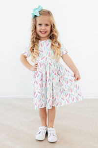 Close-up of the Color Crayons Short Sleeve Pocket Twirl Dress for Girls showing the cozy fabric and colorful crayon print.