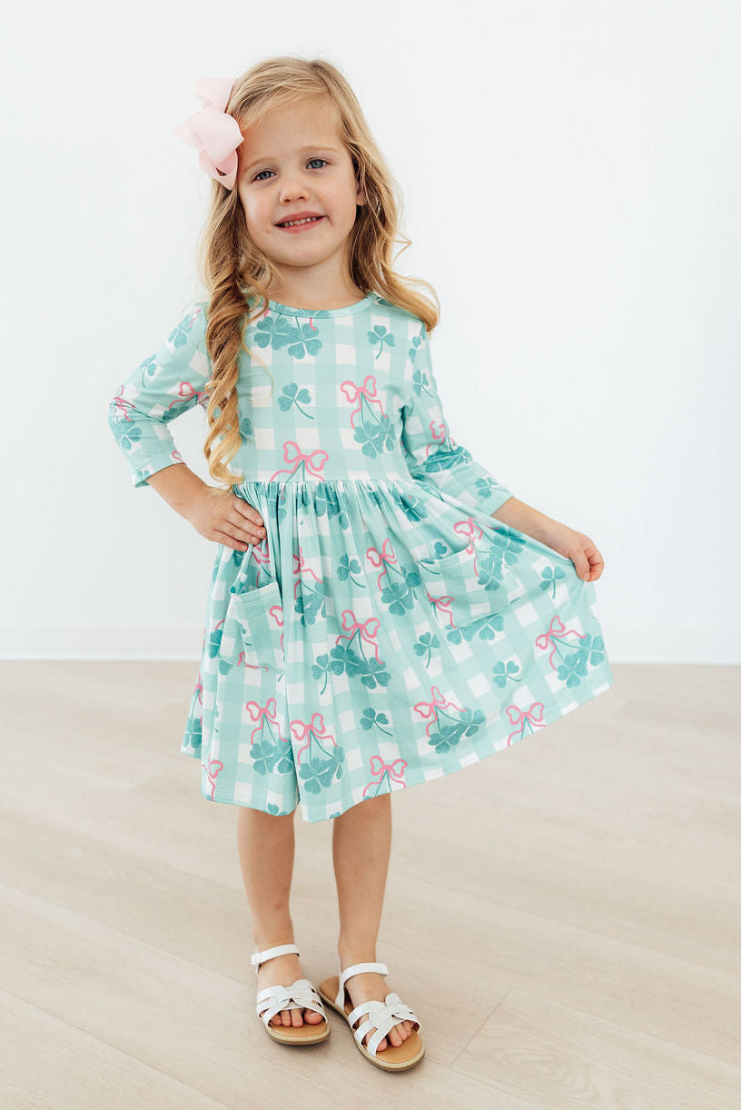The Shamrock Sweetheart 3/4 Sleeve Pocket Twirl Dress for Girls displayed on a hanger, highlighting its vibrant colors and twirl-friendly silhouette.