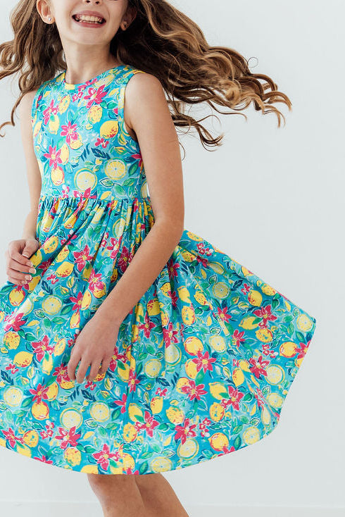 Summer Squeeze Tank Twirl Dress in turquoise tropical floral print worn by a smiling girl twirling.