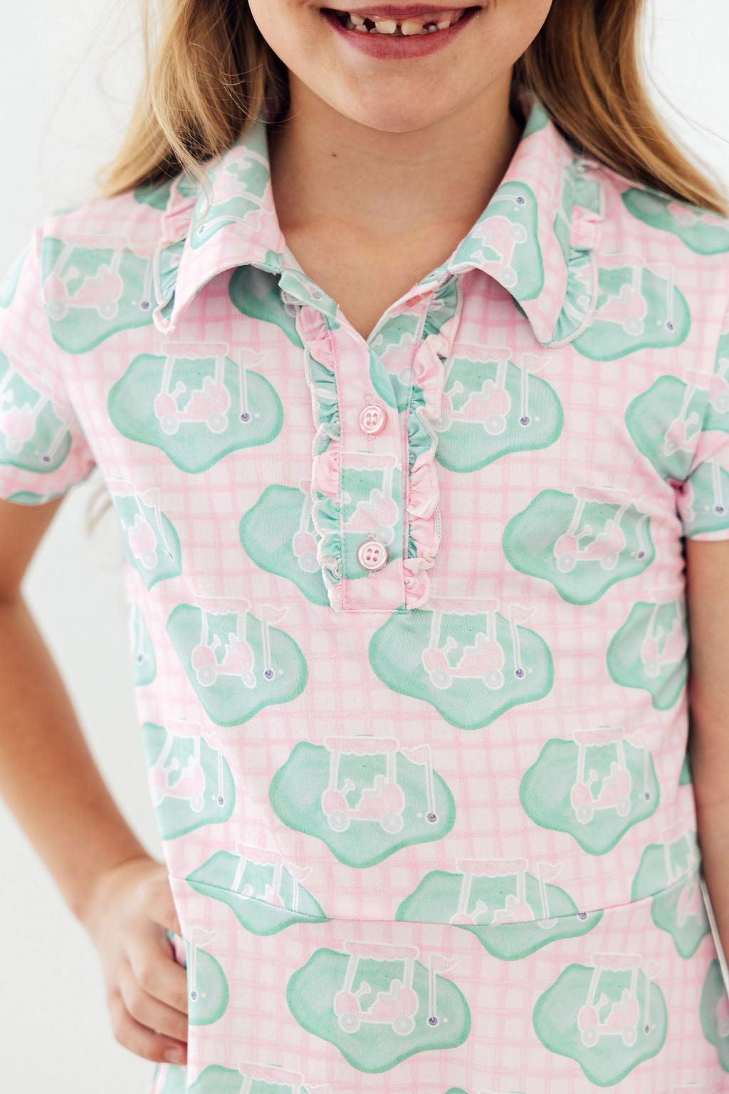 Girl wearing She's on the Green Short Sleeve Polo Dress in pink plaid with green tractor motif.