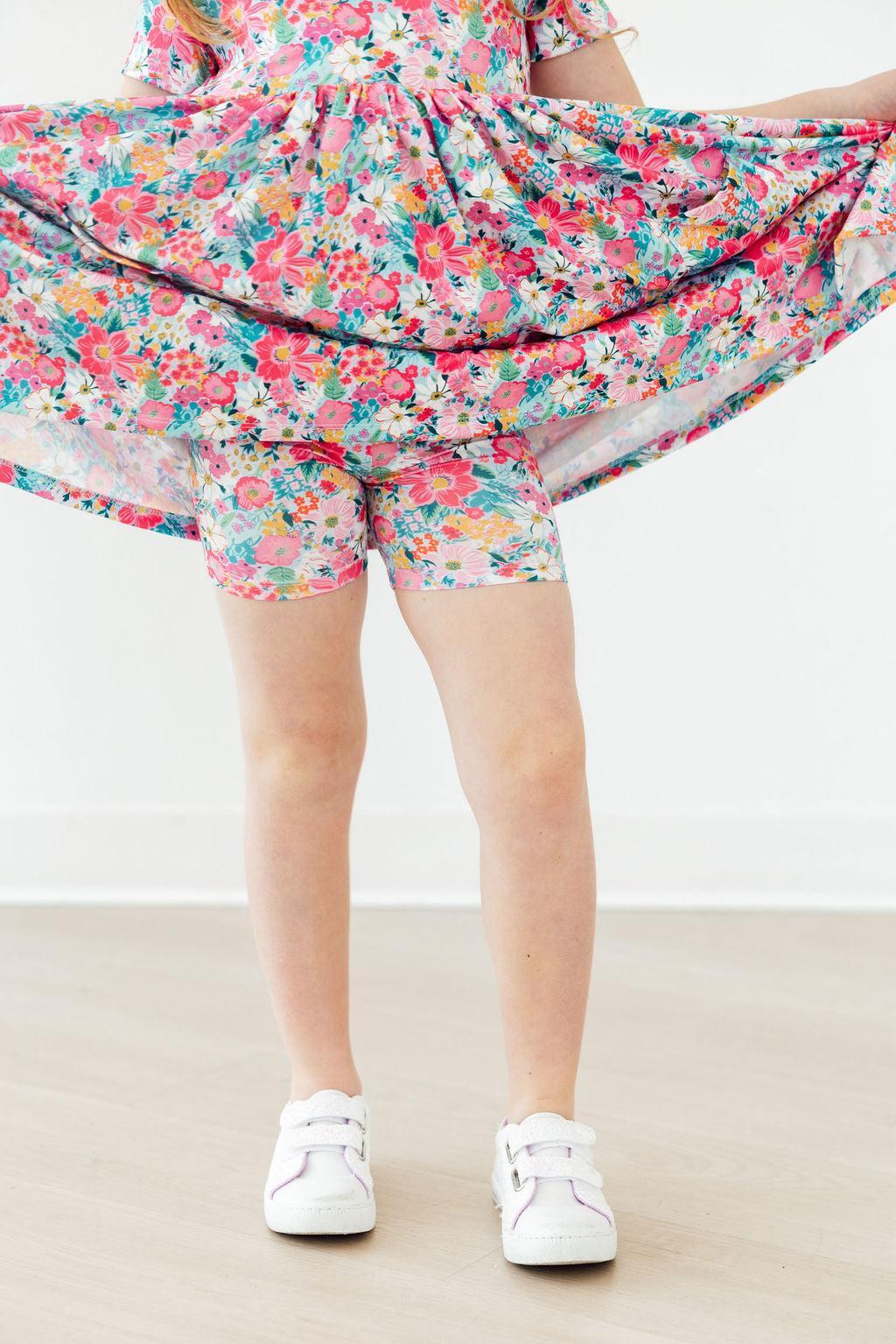 Petal Promises Short Sleeve Pocket Twirl Dress in a vibrant floral print, twirled by a toddler, with white sneakers.