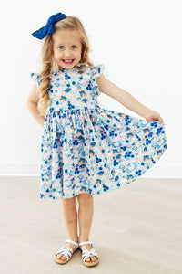 The Blueberry Picnic Flutter Sleeve Girls Twirl Dress featured in a sunny outdoor setting, demonstrating its coastal-inspired style and versatility for school or parties.