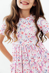 Girl wearing Whimsical Woods Short Sleeve Pocket Twirl Dress with pastel unicorn and floral print; twirl-ready.