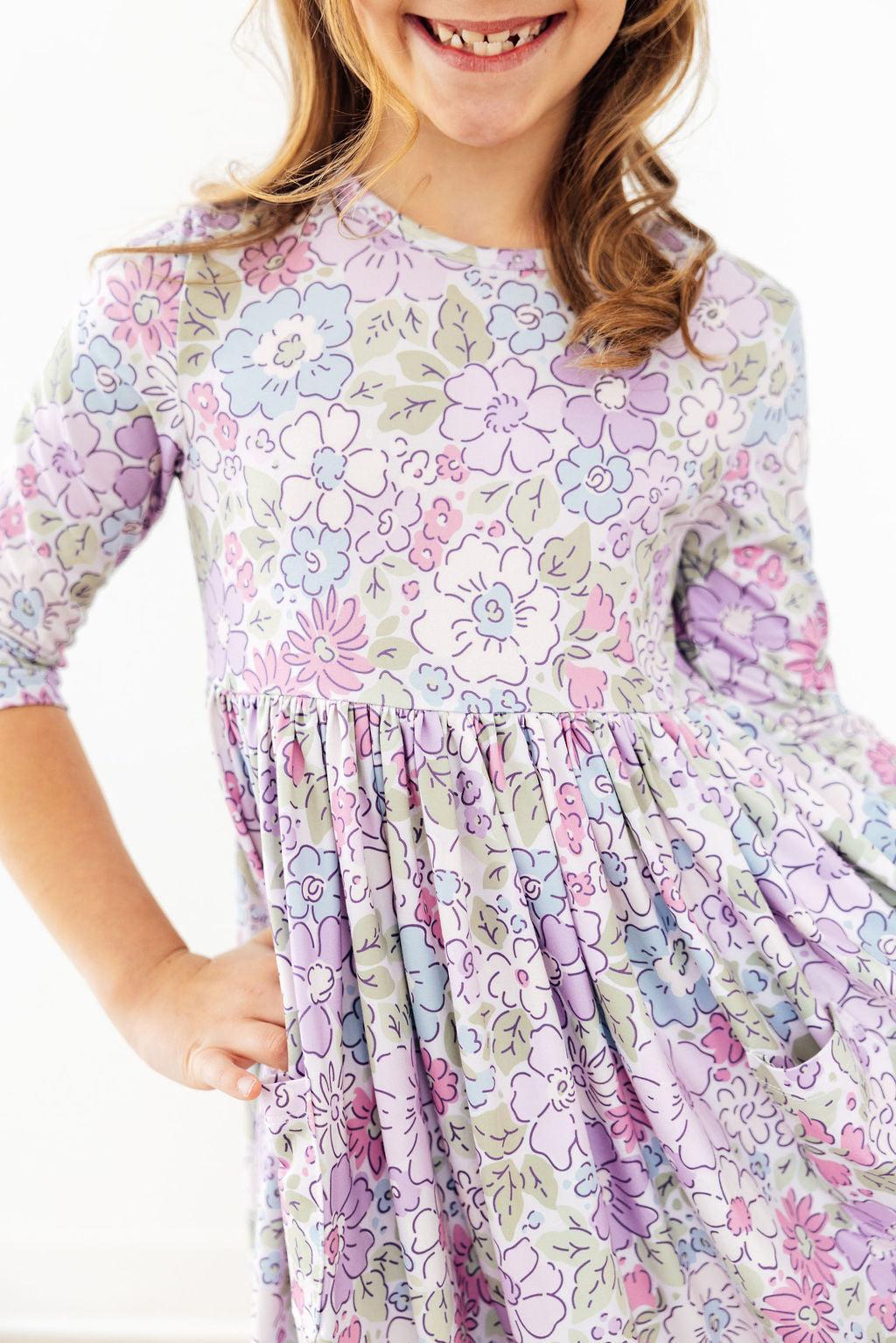 Spring Gardens 3/4 sleeve pocket twirl dress in pastel florals with scoop back on a smiling girl.