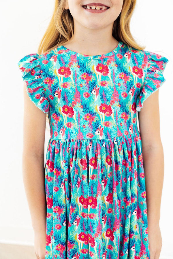 Little girl in Lovely Llamas Flutter Sleeve Twirl Dress, turquoise print with llamas and bright pink flowers.