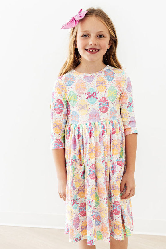 Egg-stra Cute 3/4-Sleeve Pocket Twirl Dress with scoop-back, pastel bow pattern, worn by a smiling girl.