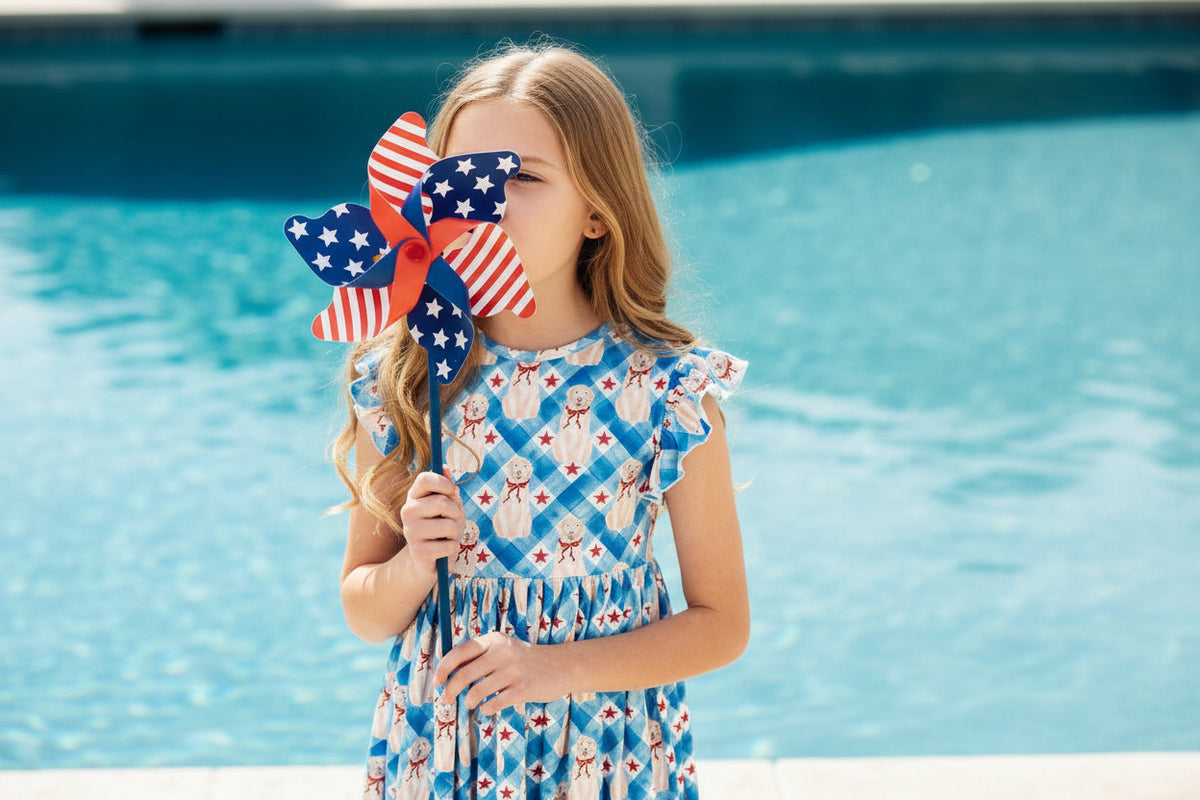 Girl in a blue dress with a red, white, and blue pinwheel on a white background