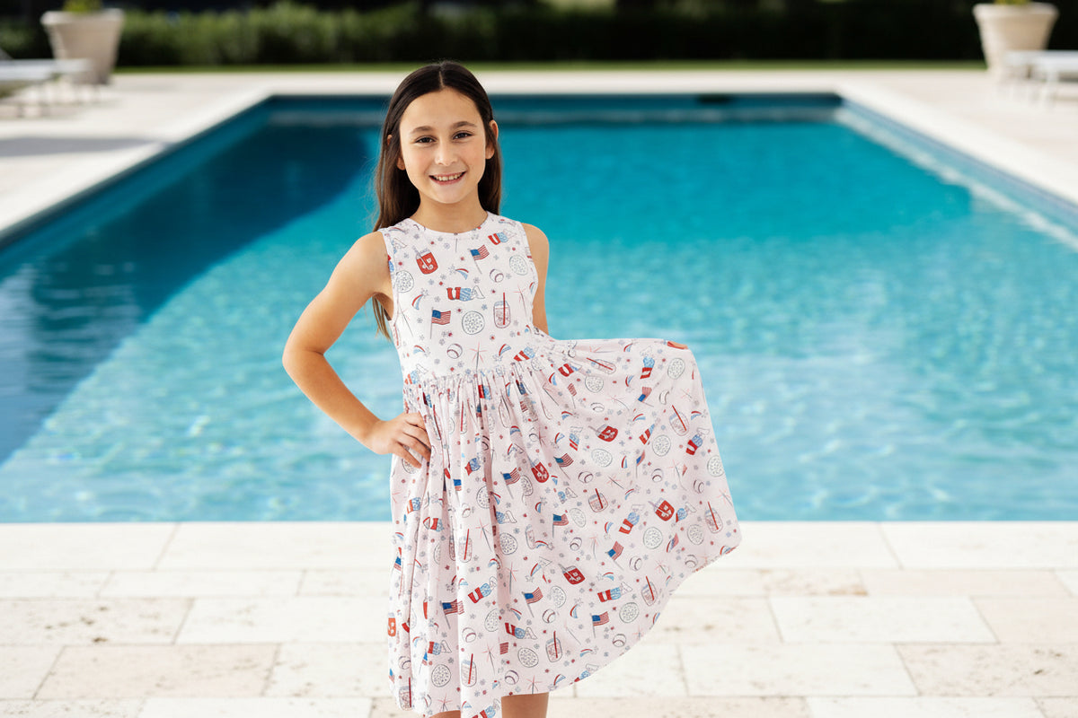 Girl wearing Born in the USA Tank Twirl Dress with patriotic print, scoop back, ballet neckline, full twirl skirt.