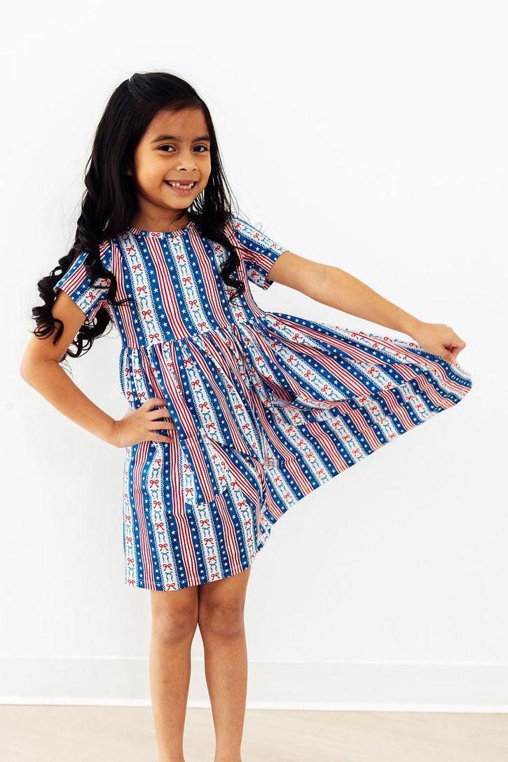 All-American Girl short sleeve pocket twirl dress on a smiling girl in patriotic blue-red striped print