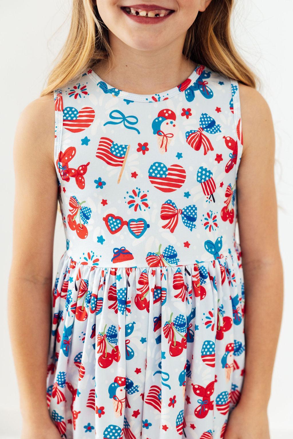 Little Miss Liberty Tank Twirl Dress on a smiling girl, patriotic print with hearts, bows, stars; full twirl skirt.
