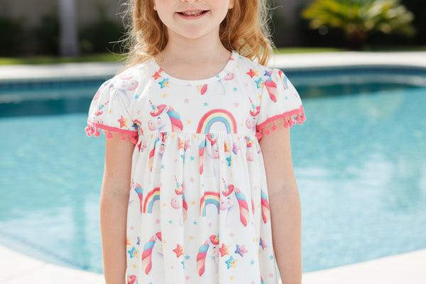 Child wearing a dress with rainbow and star patterns against a blue background