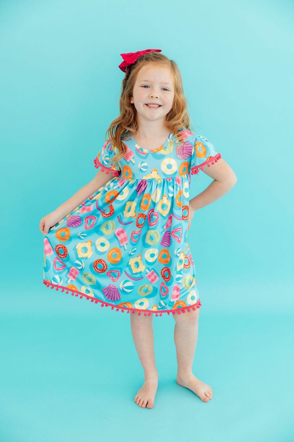 Close-up of the Fun Floaties Pom Pom Summer Dress for Girls highlighting the soft fabric and whimsical embellishments, ideal for outdoor adventures.