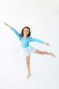 Girl dancing in a blue snowflake long sleeve twirl leotard with white skirt and ballet shoes.