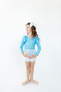 Girl wearing blue snowflake long sleeve twirl leotard with white skirt and ballet shoes for first dance class.