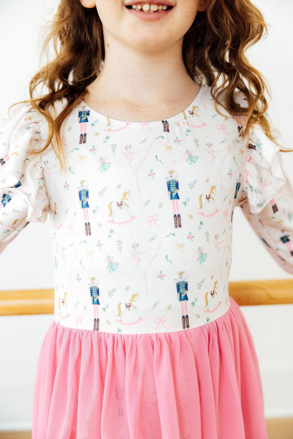 Children's long sleeve Christmas leotard with nutcracker and ballerina print, paired with a pink tulle skirt.