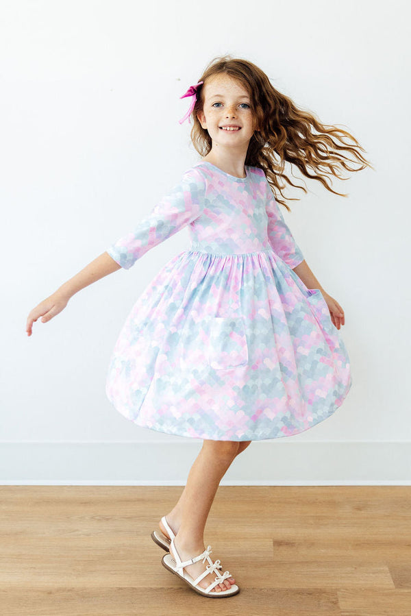 Young girl twirling in a pastel heart-print 3/4 sleeve pocket dress with a full skirt, perfect for school or play.