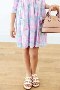 Pastel mermaid scale print 3/4 sleeve twirl dress with pockets, paired with white bow sandals and a pink handbag.