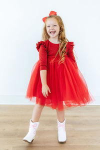 Happy girl wearing a red shimmer 3/4 sleeve tutu dress with flutter sleeves and white cowboy boots.