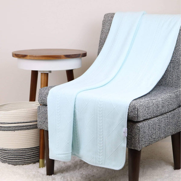 Full size mint knit throw blanket draped over gray chair showcasing soft knit texture and cable pattern